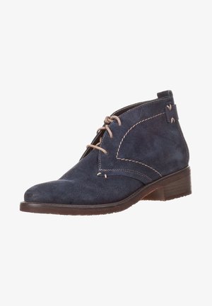 Bottine en daim bleu marine avec lacets beiges, surpiqûres contrastantes et un petit talon en bois empilé.
