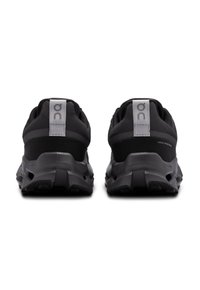 Chaussures de sport noires avec une tige en mesh, un col rembourré et une semelle en caoutchouc épaisse avec un design de traction texturé et des accents de logo.