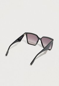 Ochelari de soare din acetat negru cu formă geometrică, lentile degradate violet și brațe elegante, ascuțite. Caracteristici de design notabile includ hardware minimal.