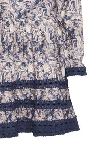 Ziedu raksta kleita ar tumši zilu pamatu, kurai ir gaiši rozā un krēmkrāsas ziedi. Iekļauts tumši zils mežģīņu apmale ar acs formām ap apakšējo malas.