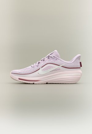 Ανοιχτό ροζ αθλητικό παπούτσι Nike με λευκό λογότυπο swoosh, αναπνεύσιμο επάνω μέρος από δίχτυ και παχιά μαξιλαρωμένη σόλα σε ουδέτερο φόντο.