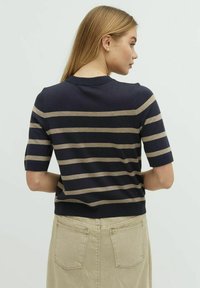 Navy och beige randig kortärmad tröja med rund halsringning. Lätt stickad tyg med en figursydd passform och ribbad nederkant.