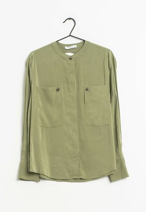 Chemise à manches longues vert olive en tissu lisse, avec un col rond, deux poches poitrine à rabat avec boutons, et un ourlet incurvé.