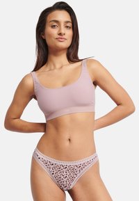 Lyserød bralette med brede stropper og glat tekstur, kombineret med matchende gennemsigtige trusser med leopardmønster og blonderkant.