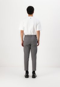 White cotton crew-neck t-shirt, gray tapered pants with elastic waistband, side and back pockets, worn with black shoes and socks.