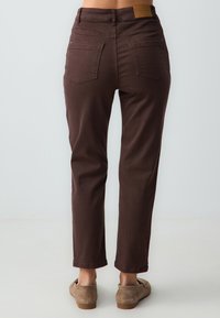 Bruine denim broek met een iets taps toelopende pijp, twee achterzakken en een leren taille-label in tan. Glad oppervlak, casual pasvorm.
