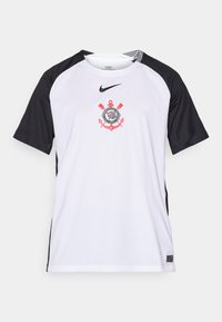 Hvit kortermet skjorte med svarte ermer, med en sentral logo med røde detaljer. Laget av pustende stoff, ideell for sport.