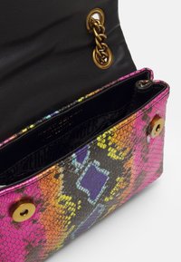 Třítónová kabelka se vzorem hadí kůže; má černý kožený interiér, zlaté kování a klopnové zapínání.