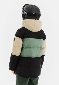 Padded Jacke in Schwarz, Beige und grün im Farbblockdesign. Mit hohem Kragen und Kapuze, aus wetterbeständigem Material gefertigt.