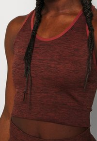 Rode gemarmerde crop tanktop met een textuurafwerking, voorzien van een contrasterende rode halslijn, terwijl het gestructureerd en aansluitend is tegen het lichaam.