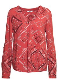 Haut rouge à manches longues avec motifs géométriques en blanc et noir, présentant une coupe ample et un décolleté en V. Texture de tissu douce.