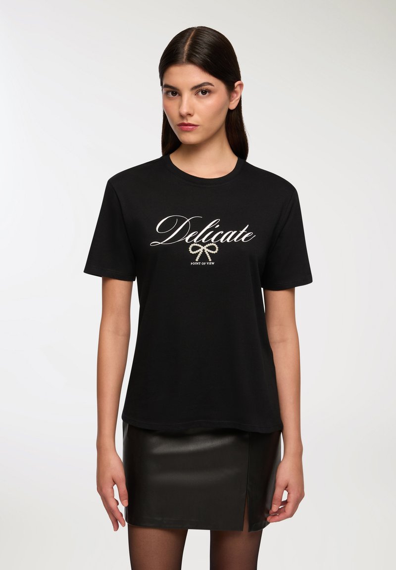 Czarna bawełniana koszulka z krótkim rękawem, z białym, pisanym ręcznie napisem "Delikatny" i graficzną wstążką poniżej. Luźny krój.