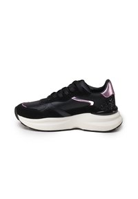 Baskets de sport noires en cuir et daim, avec une semelle épaisse blanche, des accents métalliques roses et un détail de talon noir texturé.