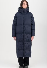 Donkerblauwe gewatteerde jas met capuchon, met een lange uitstraling, gestikte gedeelten en een rits aan de voorkant. Glad textuur met een lichte uitstraling.