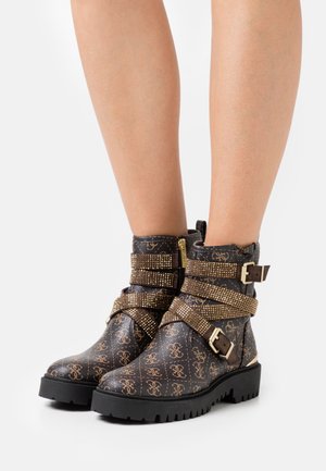 Stivali neri in pelle fino alla caviglia con cinturini decorati da borchie dorate, fibbie decorative e un motivo testurizzato. Suole in gomma spesse per garantire durata.