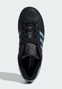 Black leather sneaker with three light blue stripes. Features a rubberized toe cap and textured tongue with embossed logo. Black laces.