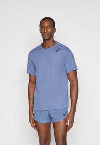 Maglietta sportiva azzurro chiaro con maniche corte, motivo testurizzato e logo Nike nero, abbinata a pantaloni corti dello stesso colore.