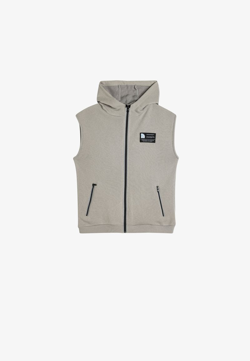 Hooded mouwloze vest in lichtgrijze stof, met een ritssluiting aan de voorkant, twee zijzakken met rits en een logopatch op de borst.