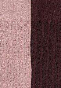 Stricksocken mit einem hellpinkfarbenen Abschnitt mit einem strukturierten diagonalen Muster und einem dunkelburgunderfarbenen Abschnitt mit einer ähnlichen gerippten Textur.