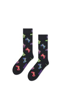 Chaussettes noires avec des motifs de manettes de jeux vidéo colorées en vert, rouge, violet et bleu. Texte "HAPPY" en violet en bas.