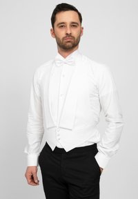 Weißes formelles Hemd mit Flügelkragen, Frontknöpfen und passender Fliege, kombiniert mit einer schwarzen Weste und Anzughose.