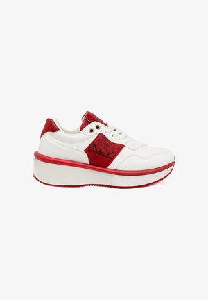 Witte sneaker met rode accenten, gewafeld rood paneel, verhoogde zool met horizontale strepen en metalen oogjes voor veters. Gedurfde logo op de zijkant.