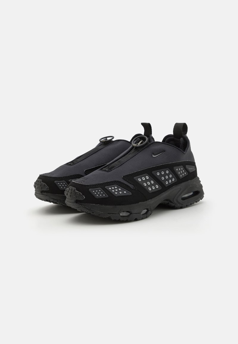 Czarne buty sportowe o smukłym designie, z teksturowaną cholewką, wyraźnymi akcentami geometrycznymi i trwałą gumową podeszwą.