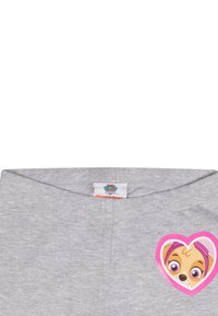 Grijze katoenen t-shirt met een roze hartvormige sticker met het gezicht van een cartoon hond en grote ogen. Label: "Paw Patrol, Nickelodeon."