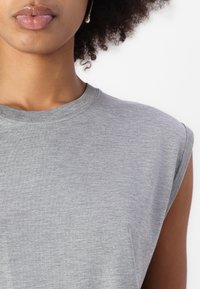 Gray sleeveless t-shirt made of soft, lightweight cotton. Features a rounded neckline and a smooth texture. No visible patterns or accents.