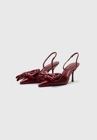 Burgundy patento nahkakengät, joissa on terävät varpaat, ja etuosassa suuret nauhat sekä kapeat stiletto-korkot.
