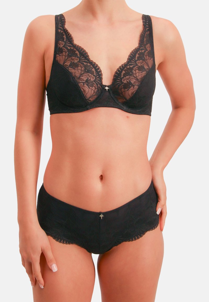 Schwarzes Spitzen-Dessous-Set mit V-Ausschnitt-BH mit Blumenmuster und passendem Slip mit gewellten Kanten. Silberne Akzentdetails in der Mitte.