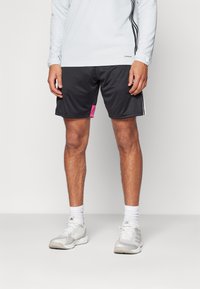Svarte shorts med rosa detaljer, med en avslappet passform og elastisk midje. Kombinert med en lys blå langermet topp og grå joggesko.