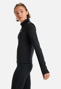 Zwarte lange mouwen sporttop met een hoge kraag, textuurstof en een aansluitend ontwerp. Voorzien van een ritssluiting aan de voorkant en een klein logo op de borst.