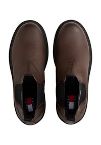 Botas de tobillo de cuero marrón con un acabado texturizado, paneles laterales elásticos y una suela de goma negra. Presenta una plantilla con marca y rayas horizontales.