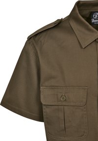 Camisa de manga corta con cuello en color verde olivo, hecha de un tejido duradero, que cuenta con un bolsillo en el pecho y hombreras.