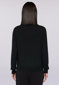 Svart stickad tröja med långa ärmar, rundad halsringning och ribbade muddars. Tyget verkar slätt och flexibelt, med en figurnära silhuett.