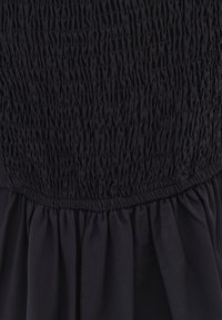 Vestido negro con fruncido recogido en el busto y falda plisada fluida. Tejido suave con una textura confortable y diseño estructurado.