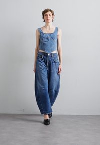 Denim odjevna kombinacija koja se sastoji od prilagođene majice bez rukava i širokih traperica. Materijal je plavi denim s glatkom teksturom.