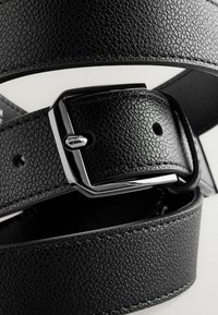 Black leather belt with a textured surface, featuring a polished silver metal buckle and multiple holes for adjustment.