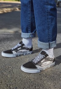 Svartvita Vans-sneakers med en blandning av texturerad tyg och slät läder, med grafiska tryck och en vit sula.