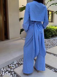Conjunto azul de duas peças que apresenta um top cropped com riscas verticais e detalhes em pérolas, combinado com calças de perna larga no mesmo padrão.