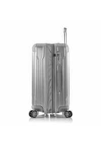 Valise rigide argentée avec surface texturée, quatre roues, poignée rétractable, serrure à combinaison et logo de la marque embossé sur le côté.