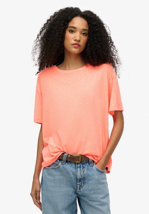 Koraalkleurige crew neck t-shirt van lichtgewicht stof, relaxed fit met korte mouwen. Gecombineerd met high-waisted lichte denim jeans en een bruine riem.