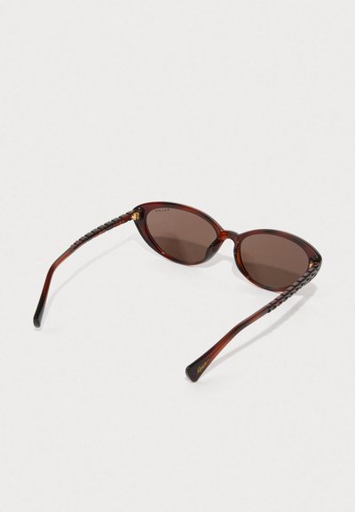 Ochelari de soare cu nuanțe de brun, cu o formă de tip cat-eye, realizați din acetat neted. Ramele au detalii împletite pe brațe și accente aurii.