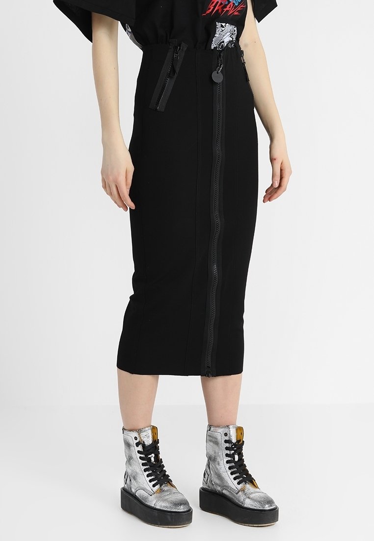 Svart midi kjol med frontdragkedja, strukturerad design och en slät textur. Matchad med metalliska silverfärgade ankelstövlar och svarta accenter.