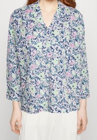 Bluse mit floralen Mustern aus einem weichen, leichten Stoff. Sie hat einen V-Ausschnitt, Dreiviertelärmel und eine helle Farbpalette aus Grün, Rosa und Blau.