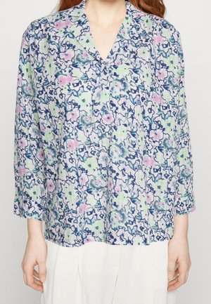 Blouse à motifs floraux avec un tissu doux et léger. Présente un col V, des manches trois-quarts et une palette de couleurs claires de vert, rose et bleu.