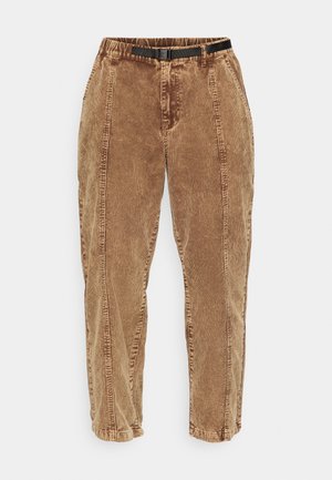 Bruine corduroy broek met een gestructureerd oppervlak, voorzien van een zwarte verstelbare riem, zijzakken en een relaxed fit. De broek tapert naar de enkels toe.