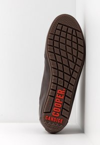 Hnědá gumová podrážka s texturovaným gripovým vzorem. "COOPER" a "CANDICE" označeno červeně. Plochý design se zaobleným okrajem.