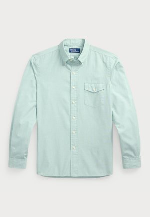 Camisa de botones de manga larga azul claro con un bolsillo, que presenta un cuello, botones frontales y tela texturizada.